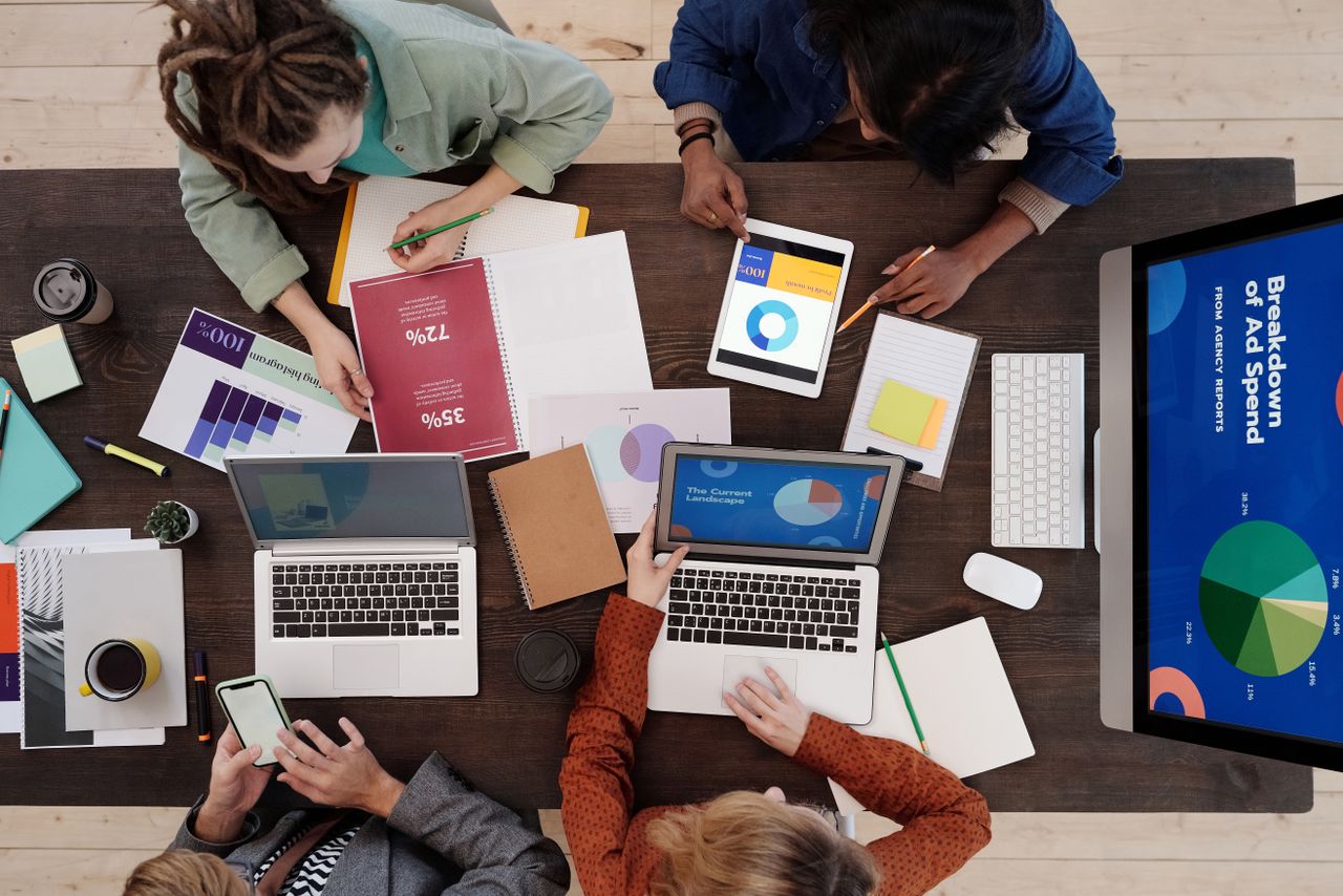 Home A diverse team collaborating on digital marketing strategies at a desk, using laptops and tablets.